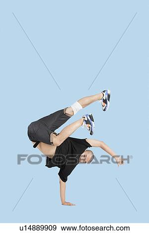 Stock Photo - Male break dancer performing handstand over blue background. Fotosearch