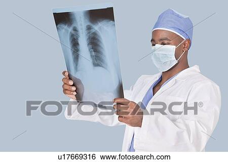 Male surgeon analyzing x-ray report over light blue background View Large Photo Image Stock Photograph - Male surgeon analyzing x-ray report over light blue background. Fotosearch