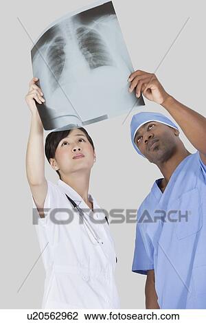 Male surgeon with nurse examining x-ray report over gray background View Large Photo Image Stock Image - Male surgeon with nurse examining x-ray report over gray background. Fotosearch