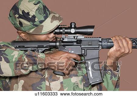 Male US Marine Corps soldier aiming M4 assault rifle over brown background View Large Photo Image Stock Image - Male US Marine Corps soldier aiming M4 assault rifle over brown background. Fotosearch