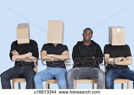 Man with friends faces covered with cardboard boxes as they sit on chairs over blue background View Large Photo Image Picture - Man with friends faces covered with cardboard boxes as they sit on chairs over blue background. Fotosearch