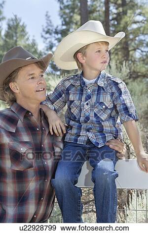 Mature father and son wearing cowboy hats looking away in park View Large Photo Image Stock Photo - Mature father and son wearing cowboy hats looking away in park. Fotosearch