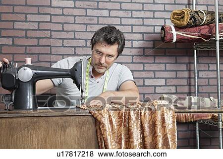 Stock Photo - Mature male dressmaker stitching cloth on sewing machine. Fotosearch