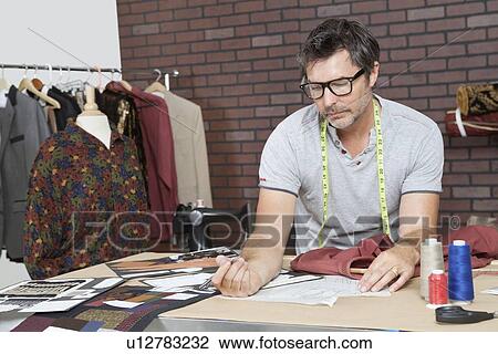 Stock Image - Mature male fashion designer working in design studio. Fotosearch