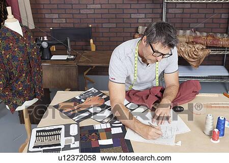 Stock Photo - Mature male fashion designer working on sketch in design studio. Fotosearch