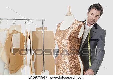 Stock Photo - Mature male tailor working on an outfit in design studio. Fotosearch