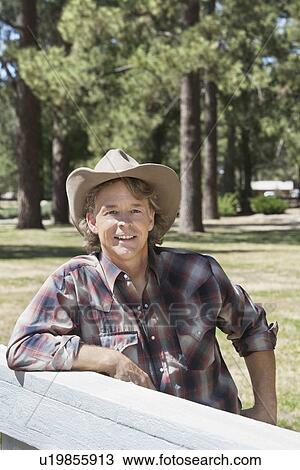 Mature man wearing cowboy hat leaning on wooden slab View Large Photo Image Stock Image - Mature man wearing cowboy hat leaning on wooden slab. Fotosearch