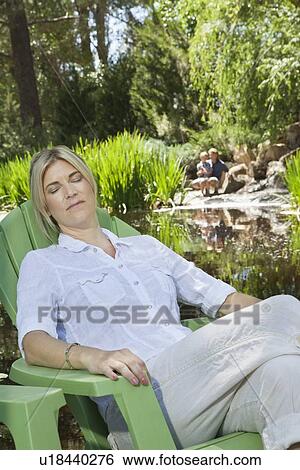 Mature woman resting in chair with man and son fishing in the background View Large Photo Image Stock Photograph - Mature woman resting in chair with man and son fishing in the background. Fotosearch