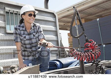 Mid adult woman holding a break hose of a flatbed truck View Large Photo Image Stock Photo - Mid adult woman holding a break hose of a flatbed truck. Fotosearch
