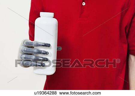 Stock Photo - Mid section of a man holding bottle with prosthetic hand over gray background. Fotosearch