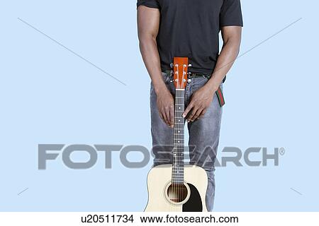 Mid section of an African American man with guitar over light blue background View Large Photo Image Picture - Mid section of an African American man with guitar over light blue background. Fotosearch