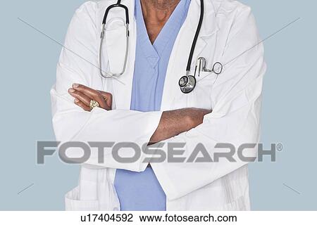 Midsection of a doctor with arms crossed over light blue background View Large Photo Image Stock Image - Midsection of a doctor with arms crossed over light blue background. Fotosearch