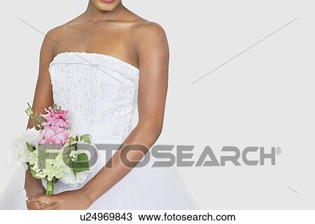Midsection of bride holding bouquet over gray background View Large Photo Image Stock Image - Midsection of bride holding bouquet over gray background. Fotosearch