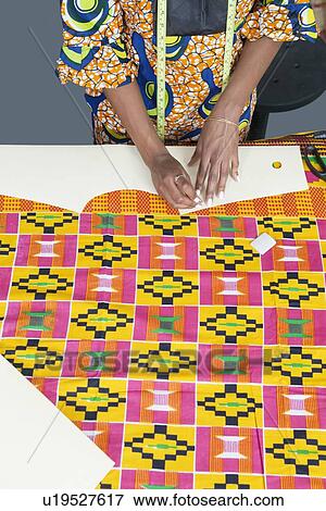 Stock Photo - Midsection of female fashion designer marking pattern with chalk on fabric textile. Fotosearch