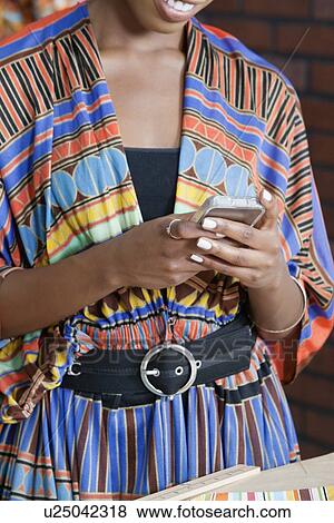 Midsection of woman in traditional African print attire using cell phone View Large Photo Image Stock Photo - Midsection of woman in traditional African print attire using cell phone. Fotosearch