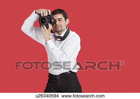 Mixed race man taking picture with digital camera over red background View Large Photo Image Picture - Mixed race man taking picture with digital camera over red background. Fotosearch