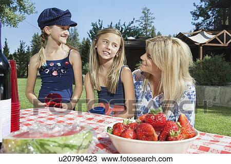 Mother communicating with daughters while sitting at outdoor dining table View Large Photo Image Stock Image - Mother communicating with daughters while sitting at outdoor dining table. Fotosearch