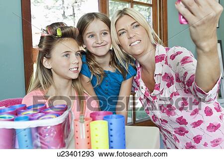 Mother with daughters taking self portrait with cell phone View Large Photo Image Stock Image - Mother with daughters taking self portrait with cell phone. Fotosearch