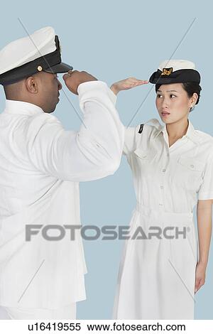 Stock Photography - Multi-ethnic US Navy officers saluting each other over light blue background. Fotosearch