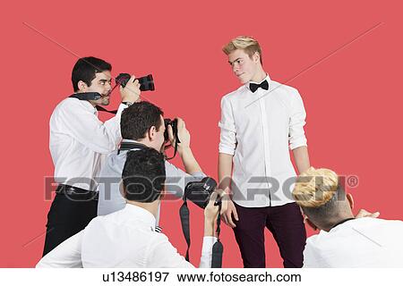 Paparazzi taking photographs of male actor over red background View Large Photo Image Stock Photo - Paparazzi taking photographs of male actor over red background. Fotosearch