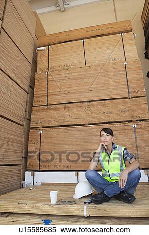 Pensive female industrial worker sitting cross-legged on wooden planks View Large Photo Image Stock Photography - Pensive female industrial worker sitting cross-legged on wooden planks. Fotosearch