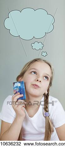 Pensive young girl holding credit card with speech bubble over gray background View Large Photo Image Stock Image - Pensive young girl holding credit card with speech bubble over gray background. Fotosearch