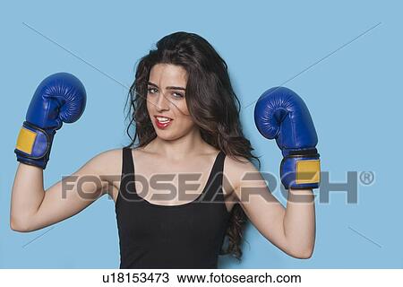 Portrait of a beautiful young female boxer raising arms in victory against blue background View Large Photo Image Stock Image - Portrait of a beautiful young female boxer raising arms in victory against blue background. Fotosearch