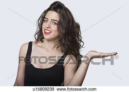 Portrait of a beautiful young woman holding her palm out over gray background View Large Photo Image Stock Photo - Portrait of a beautiful young woman holding her palm out over gray background. Fotosearch