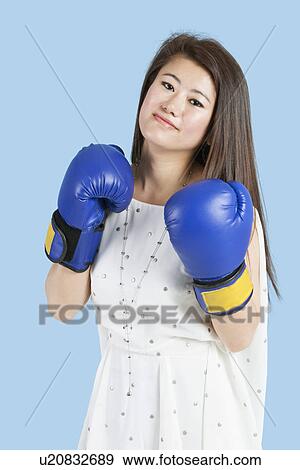 Portrait of a beautiful young woman wearing boxing gloves over blue background View Large Photo Image Stock Photo - Portrait of a beautiful young woman wearing boxing gloves over blue background. Fotosearch
