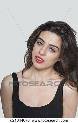Stock Photograph - Portrait of a beautiful young woman over gray background. Fotosearch