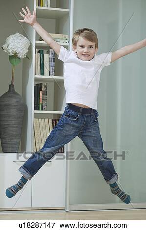 Stock Photo - Portrait of a boy in casuals jumping in mid-air at home. Fotosearch