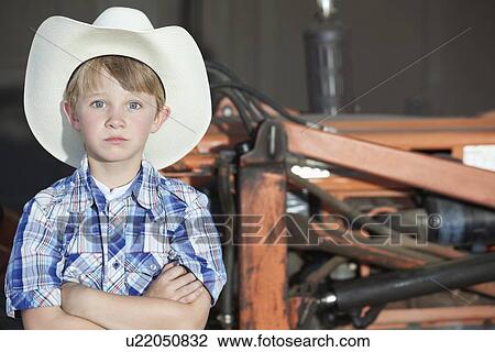 Portrait of a boy wearing cowboy hat while standing with arms crossed against machine View Large Photo Image Stock Image - Portrait of a boy wearing cowboy hat while standing with arms crossed against machine. Fotosearch