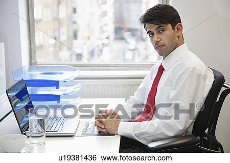 Portrait of a confident businessman at office desk View Large Photo Image Stock Photograph - Portrait of a confident businessman at office desk. Fotosearch