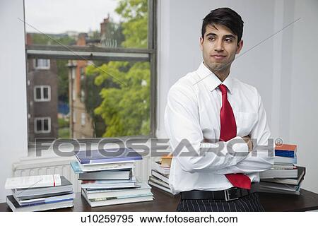 Portrait of a confident businessman with arms crossed looking away in office View Large Photo Image Stock Photography - Portrait of a confident businessman with arms crossed looking away in office. Fotosearch