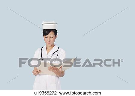 Portrait of a female doctor reading medical report over light blue background View Large Photo Image Stock Image - Portrait of a female doctor reading medical report over light blue background. Fotosearch