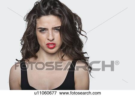 Portrait of a frustrated young female against gray background View Large Photo Image Stock Photo - Portrait of a frustrated young female against gray background. Fotosearch
