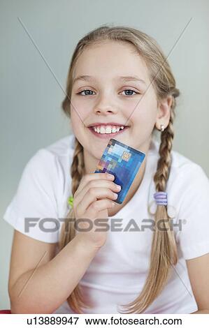 Portrait of a girl holding credit card over gray background View Large Photo Image Stock Photo - Portrait of a girl holding credit card over gray background. Fotosearch