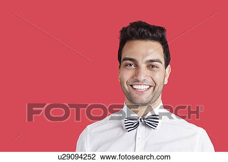 Portrait of a happy mid adult man wearing bow-tie over red background View Large Photo Image Stock Image - Portrait of a happy mid adult man wearing bow-tie over red background. Fotosearch