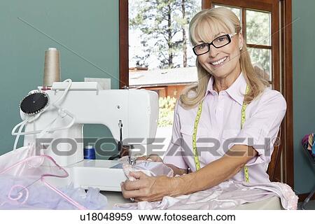 Stock Photo - Portrait of a happy senior woman sewing. Fotosearch