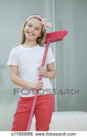 Stock Photograph - Portrait of a happy young girl with broom. Fotosearch