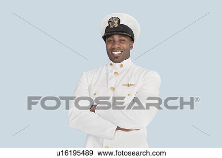 Portrait of a happy young US Navy officer with arms crossed over light blue background View Large Photo Image Stock Photo - Portrait of a happy young US Navy officer with arms crossed over light blue background. Fotosearch