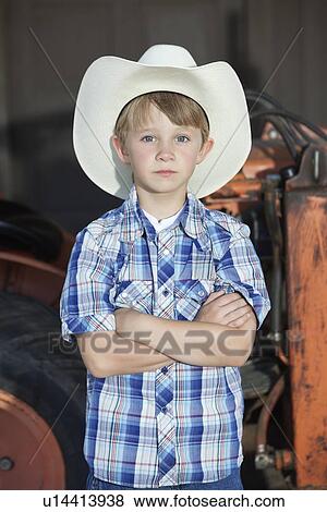 Portrait of a little boy wearing cowboy hat while standing with arms crossed against machine View Large Photo Image Stock Photo - Portrait of a little boy wearing cowboy hat while standing with arms crossed against machine. Fotosearch