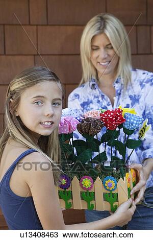 Portrait of a little girl handing over artificial flowers in crate to mother View Large Photo Image Stock Image - Portrait of a little girl handing over artificial flowers in crate to mother. Fotosearch