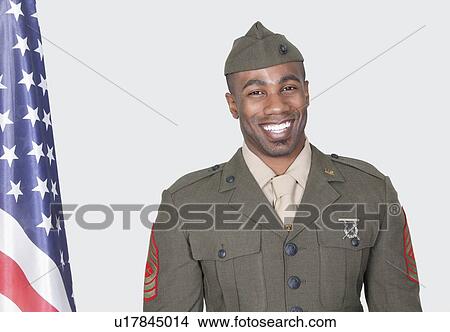 Portrait of a male US soldier smiling with American flag over gray background View Large Photo Image Picture - Portrait of a male US soldier smiling with American flag over gray background. Fotosearch
