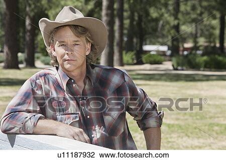 Portrait of a mature man wearing cowboy hat leaning on wooden slab View Large Photo Image Stock Image - Portrait of a mature man wearing cowboy hat leaning on wooden slab. Fotosearch