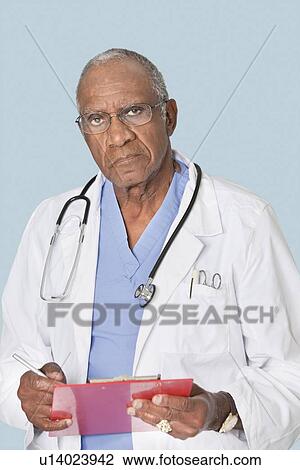 Portrait of a senior doctor holding clipboard over light blue background View Large Photo Image Stock Image - Portrait of a senior doctor holding clipboard over light blue background. Fotosearch