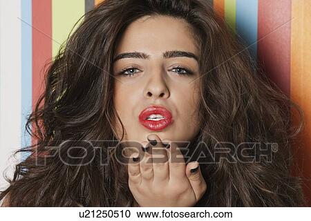 Portrait of a sensuous young woman blowing a kiss against striped background View Large Photo Image Stock Image - Portrait of a sensuous young woman blowing a kiss against striped background. Fotosearch