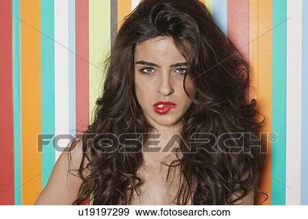 Portrait of a sensuous young woman biting lips against colorful striped background View Large Photo Image Stock Photo - Portrait of a sensuous young woman biting lips against colorful striped background. Fotosearch