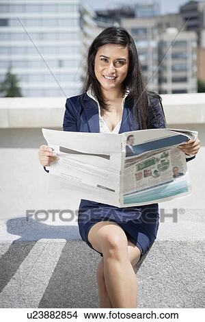 Portrait of a smart Indian businesswoman holding newspaper as she sits outdoors View Large Photo Image Picture - Portrait of a smart Indian businesswoman holding newspaper as she sits outdoors. Fotosearch
