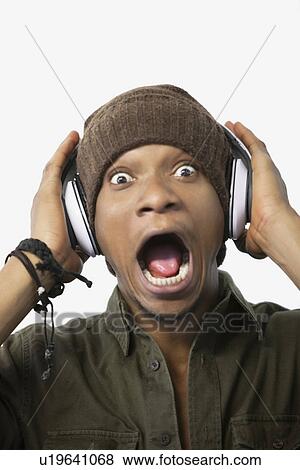 Portrait of a surprised young African American man listening music through headphones View Large Photo Image Stock Photo - Portrait of a surprised young African American man listening music through headphones. Fotosearch